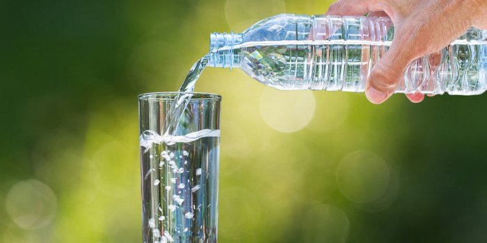 man's hand pouring water into glass on blurred bokeh background