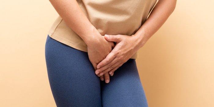 closeup sick woman with hands holding pressing her crotch isolated on background