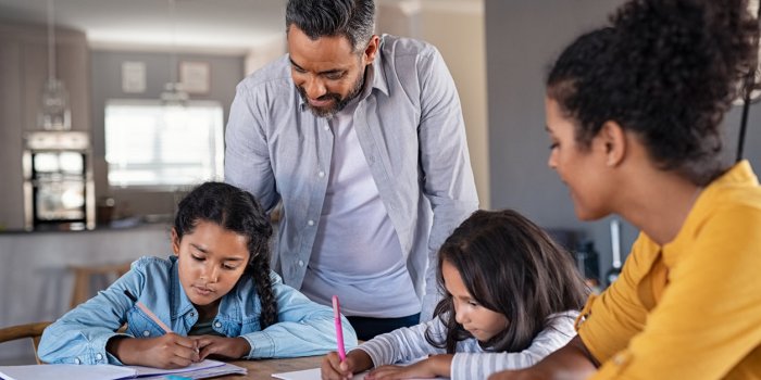 indian parents helping children with their homework at home middle eastern father and african mother helping daughters st...