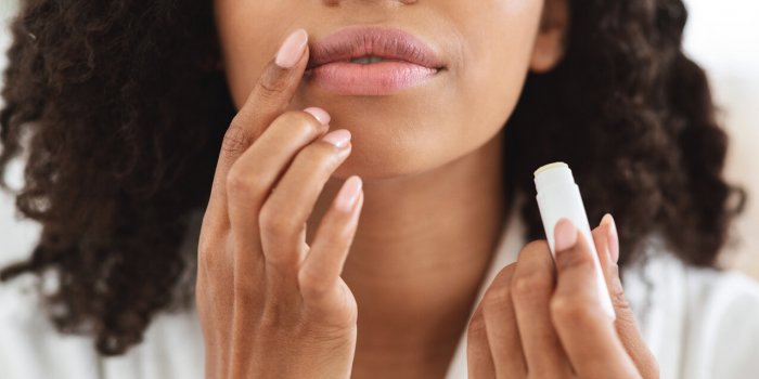lip care unrecognizable black woman applying moisturising chapstick on lips, cropped image, closeup