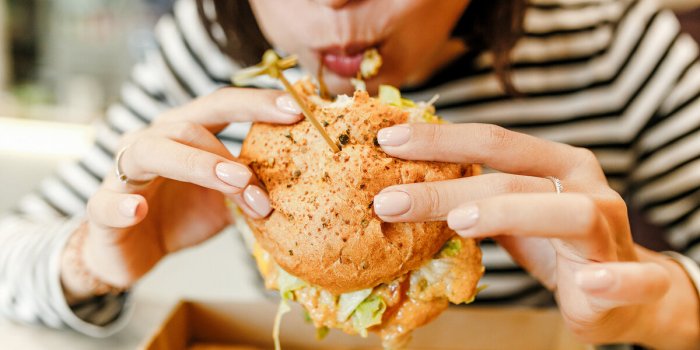 woman eating a hamburger in modern fastfood cafe, lunch concept