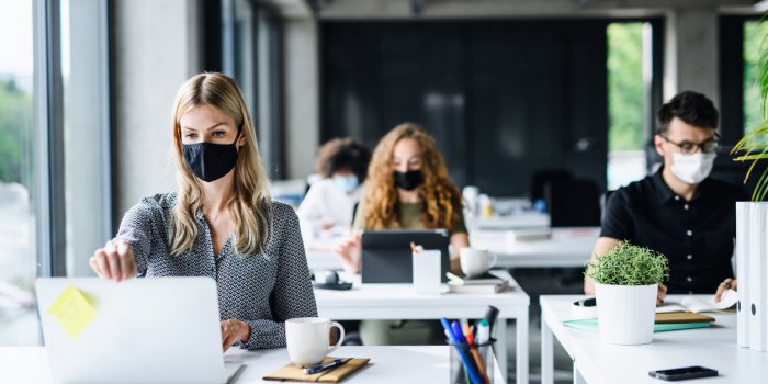 young people with face masks back at work in office after coronavirus quarantine and lockdown