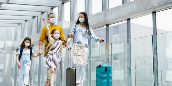 happy family with two children going on holiday, wearing face masks at the airport