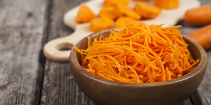 grate carrots in a bowl on a wooden table tasty and healthy food diet