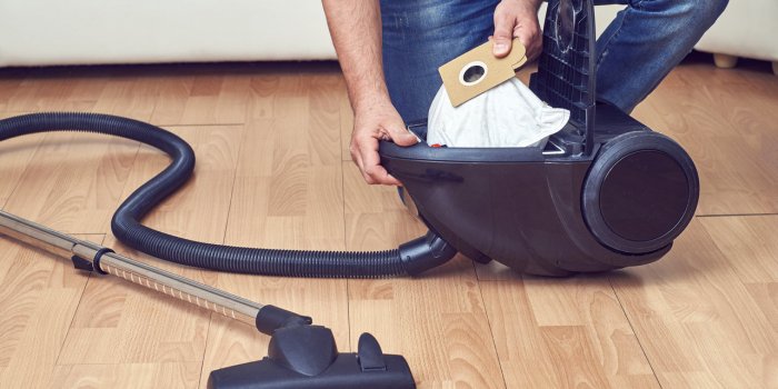 man taking out a full dust bag from a vacuum cleaner
