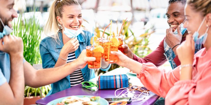 friends drinking spritz at cocktail bar with face masks - new normal friendship concept with happy people having fun toge...