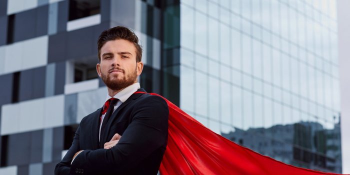 businessman in a superhero costume against a business building background