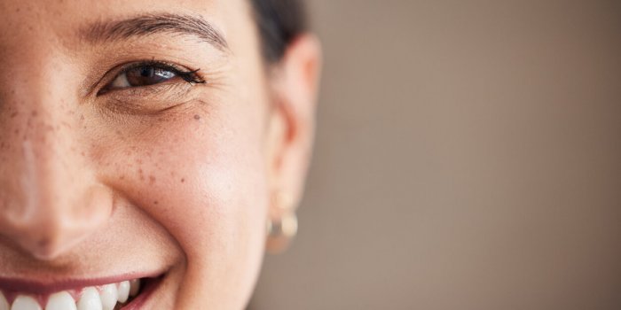 face of beautiful mixed race woman smiling with white teeth portrait of a woman's face with brown eyes and freckles posin...