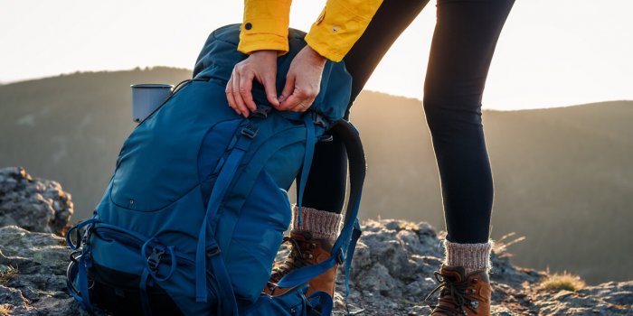 woman opening backpack after climbing mountain peak hiking outdoors female tourist unpacking rucksack