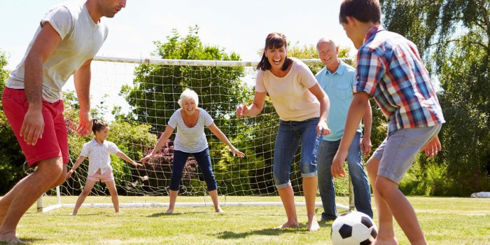 Many generations are playing football in the garden together