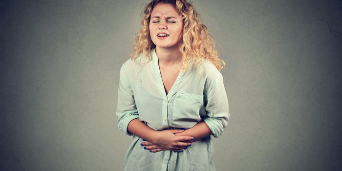 portrait young woman hands on stomach having bad aches pain isolated on gray wall background food poisoning, influenza, c...