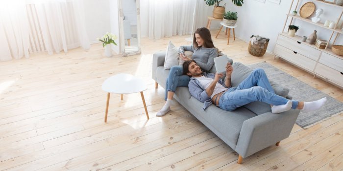 young family of two relaxing on sofa at home on weekend, panorama with free space