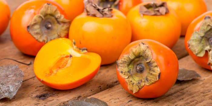 fresh ripe persimmon on a wooden table - selective focus