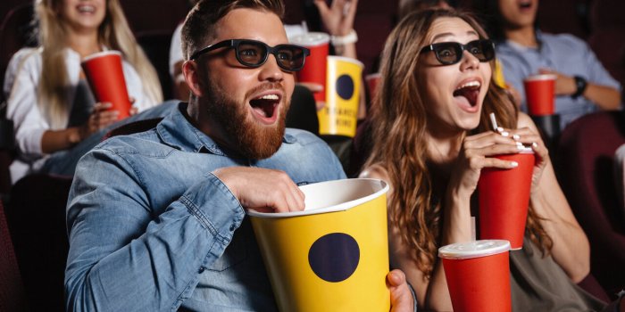 image of laughing friends sitting in cinema watch film eating popcorn and drinking aerated sweet water
