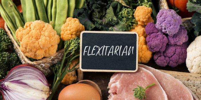 closeup of a signboard with the text flexitarian on a pile of some different raw vegetables, such as cauliflower of diffe...
