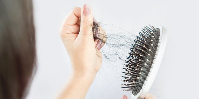 asian woman hand holding hair loss falling on comb