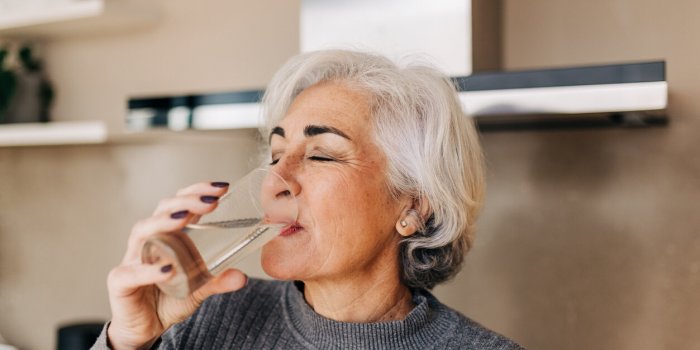 elderly woman drinking fresh tap water from a glass grey-haired mature woman staying healthy and hydrated at home