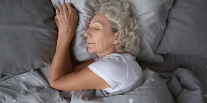 above top view calm peaceful elderly mature hoary woman sleeping on soft pillow under blanket, enjoying sweet dreams at n...
