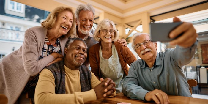 multiracial group of happy senior people taking selfie with cell phone in nursing home