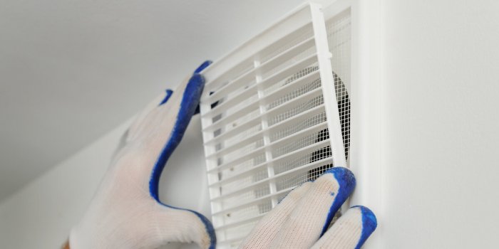 worker installs ventilation grille on the wall