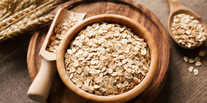 rolled oats, organic oat flakes in wooden bowl and golden wheat ears on wooden background healthy lifestyle, healthy eati...