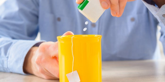 sweetener tablets and hand with box whit cup of tea