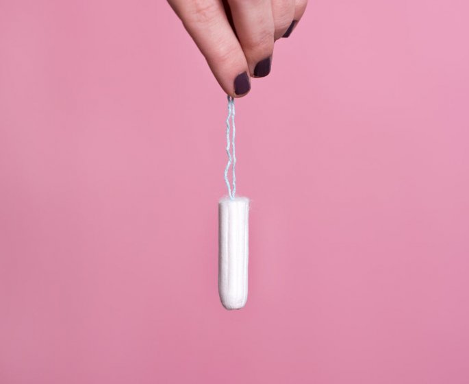 woman-s hand holding a clean cotton tampon