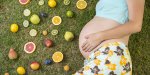 pregnant woman is laying on grass with fruit