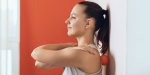 beautiful woman performs myofascial release of hyper-flexible muscles of the back with a massage ball near the wall the c...