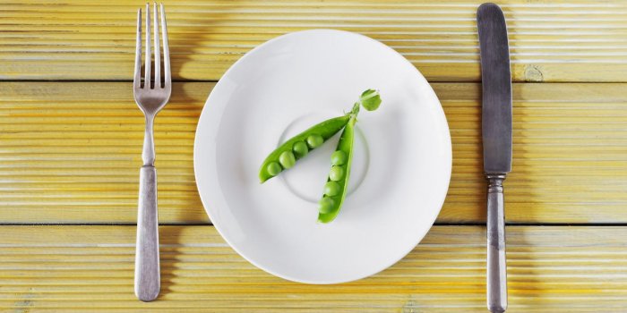 pois verts frais sur une assiette blanche et ustensiles vintage sur fond en bois coloré bio concept d'alimentation saine...