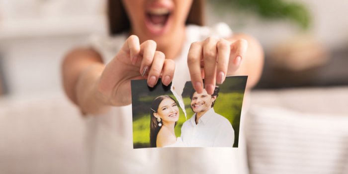 divorce concept unrecognizable furious girl tearing apart photo of happy couple indoor selective focus, panorama, cropped