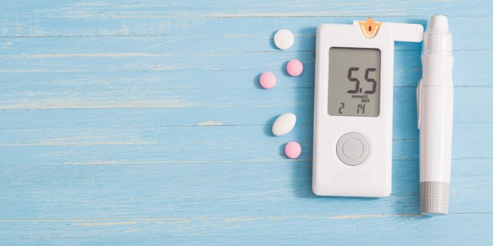 glucometer and pills on blue wooden background