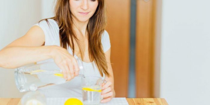 drink water woman's hand pouring fresh pure water with pieces of lemon from pitcher into glass in the morning health and ...