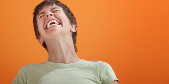 jeune femme en chemise verte incapable de contrôler son rire