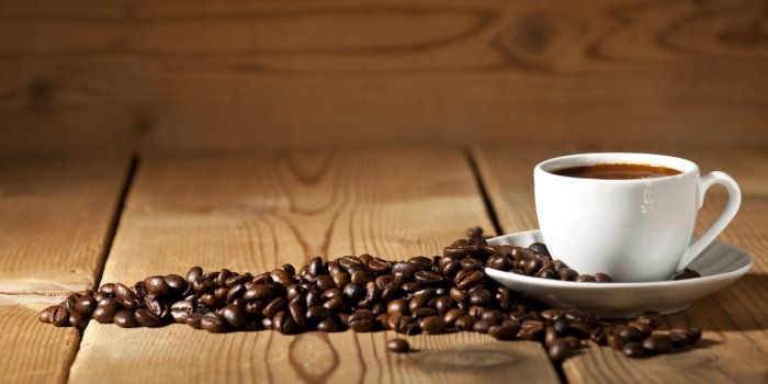 tasse à café blanche et grains de café sur le vieux fond en bois