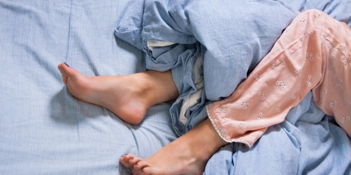 pieds féminins avec pyjama dans le lit au matin dans les draps bleus