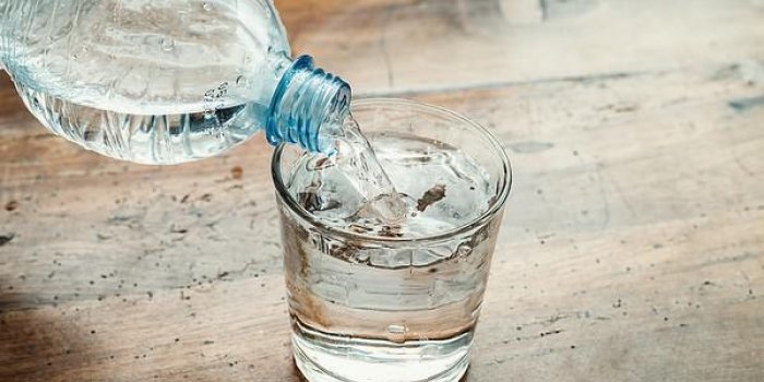 bouteille d'eau bleue versée dans un verre transparent