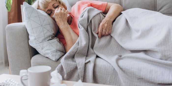 senior woman being sick having flu lying on sofa sick older lady lying in bed with high fever
