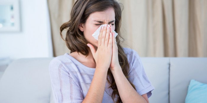 femme malade soufflant son nez à la maison dans le salon