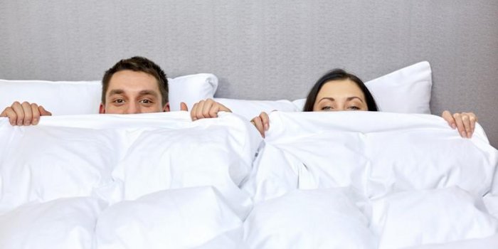 personnes, heure du coucher, confort et relations concept - concept - couple heureux se cachant sous la couverture au lit