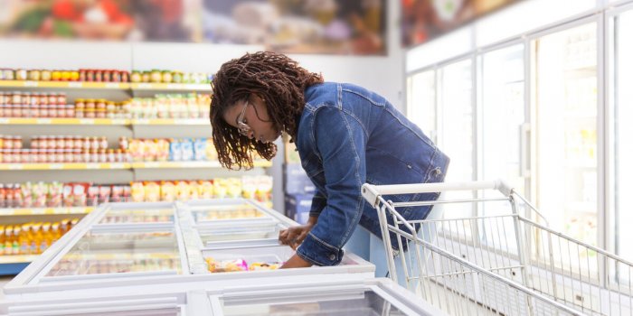 focused african american woman looking at freezer serious young customer choosing goods in supermarket shopping concept