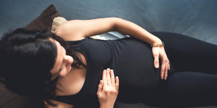 portrait de future mère portant sur le lit, concept de tir de maternité heureuse femme enceinte tenant le ventre