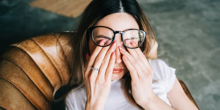 young woman rubs her eyes after using glasses eye pain or fatigue concept