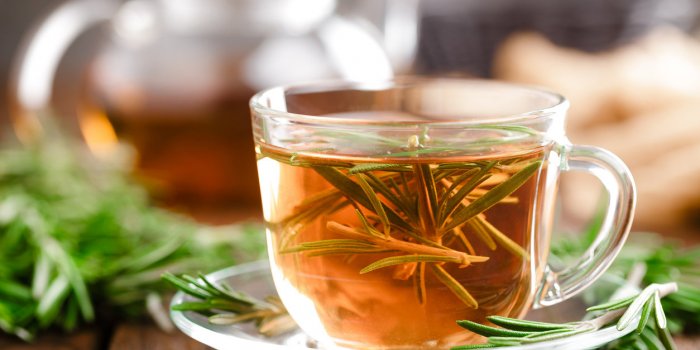 rosemary tea in glass tea cup on rustic wooden table closeup herbal vitamin tea