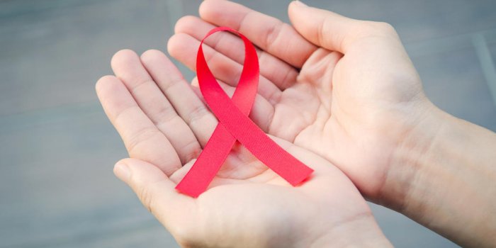 female hands holding red ribbon hiv, aids awareness ribbon, healthcare and medicine concept retro effect