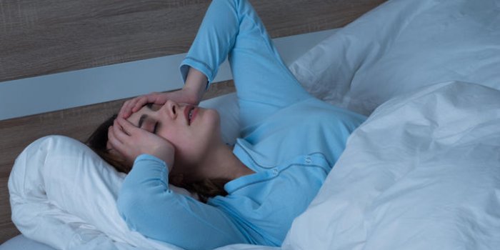 jeune femme souffrant de maux de tête allongé sur le lit