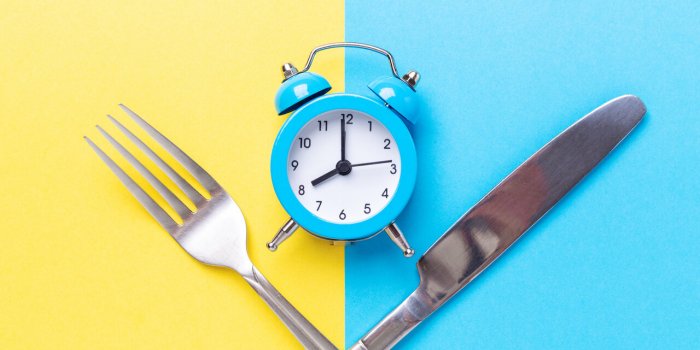 blue alarm clock, fork, knife on colored paper background intermittent fasting concept - image