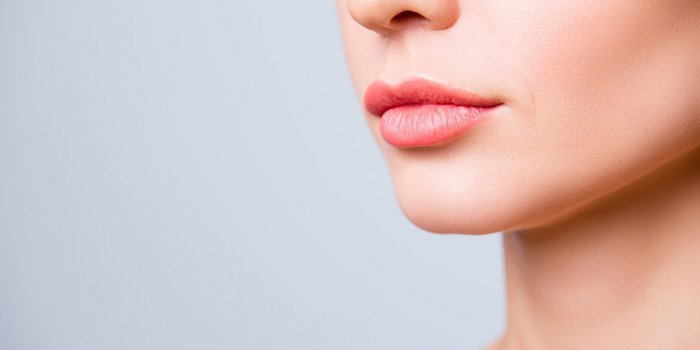 cropped close up photo of beautiful woman's lips with shape correction, isolated on grey background, copyspace
