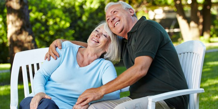 zwei lachende senioren sitzen glücklich im grünen garten