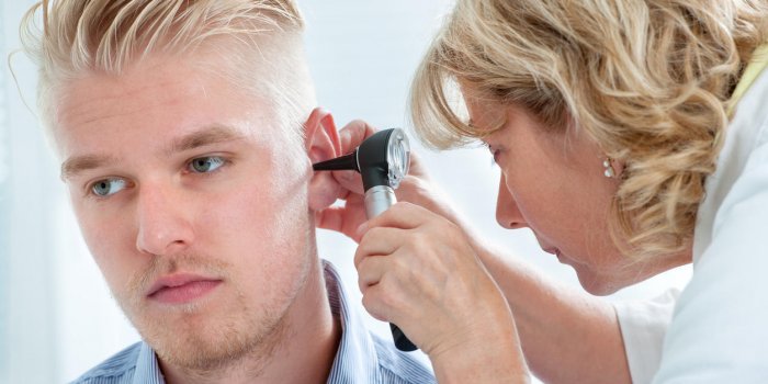 un médecin examine l'oreille du patient avec un instrument